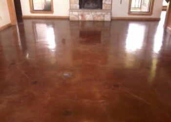 Finished polished concrete floor in a living room with fireplace and large windows. Polished concrete floor in a living room with fireplace and windows.