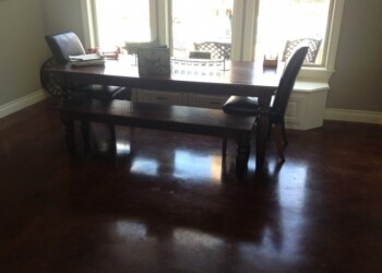 Dining room with dark stained concrete floor and large windows in a home. Dining room with dark stained concrete floor and large windows.