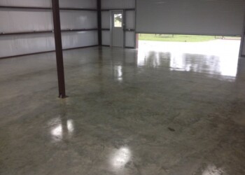 Finished concrete floor inside a metal building in Eads, Tennessee. Empty concrete floor inside a metal building with open garage door.