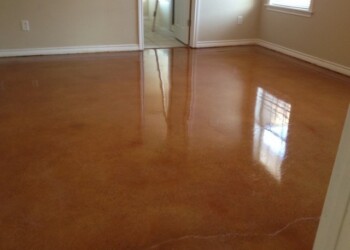 Finished acid stained concrete floor in a residential interior, reflecting light from windows. Interior room with freshly acid stained concrete floor in a neutral color.