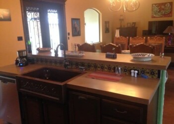 Kitchen island with beige countertop and dark wood base in a home dining area. Kitchen island with dark wood base and beige countertop in a home.