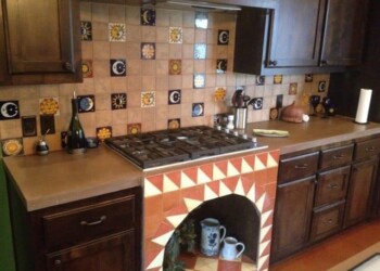Kitchen featuring a decorative tile backsplash and dark wood cabinets, part of a countertop installation in Ephrata. Kitchen with colorful tiled backsplash and dark wood cabinets in a home in Ephrata.