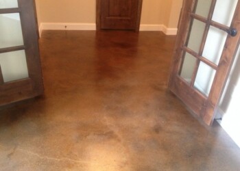 Finished acid stained concrete floor in a home, seen through open wooden French doors. Interior view of a concrete floor with acid stain finish in a home.