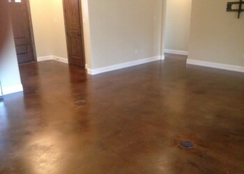 Finished concrete floor with acid stain in a home in Euless, Texas. Interior of a room with polished concrete floor and beige walls in a residential home.