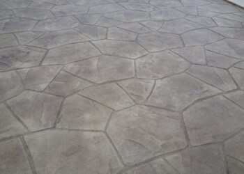 Finished stamped concrete patio with stone pattern in a residential yard. Stamped concrete patio with a stone pattern in a residential yard.