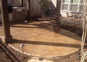 Finished concrete patio with acid stain in a backyard, featuring outdoor furniture and landscaping. Concrete patio with acid stain finish in a backyard with outdoor furniture and landscaping.