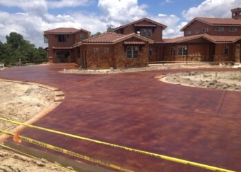 Newly stained concrete driveway in front of brick houses in a residential neighborhood. Concrete driveway with acid stain finish in front of new brick houses in a residential area.