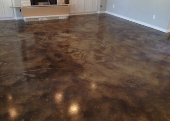 Finished acid stained concrete floor in a home, showing a rich, variegated brown and black pattern. Interior concrete floor with acid stain finish in a residential living room.
