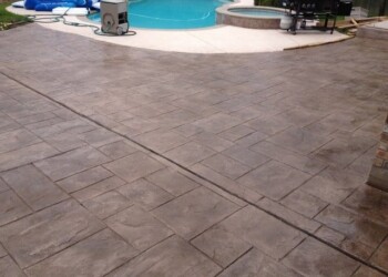 Finished stamped concrete patio around the pool in a residential backyard. Stamped concrete patio with a pool in the background in a residential backyard.