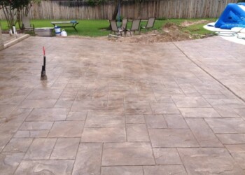 Finished stamped concrete patio with outdoor furniture and a small inflatable pool. Stamped concrete patio in a backyard with outdoor furniture and a small inflatable pool.