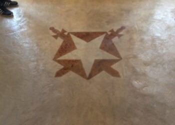 Concrete floor with a star and reindeer design near the entrance. Decorative star and reindeer design embedded in concrete floor near black double doors.