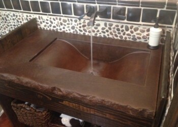 Rustic wooden kitchen sink with running water and soap dispenser in a modern kitchen. Rustic wooden kitchen sink with running water and soap dispenser in a modern kitchen.