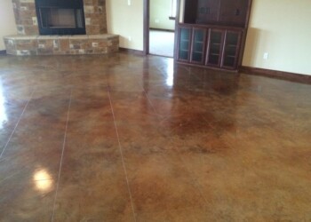 Finished acid stained concrete floor in a living room, showing a rich, variegated brown color. Interior view of a concrete floor with acid stain finish in a living room.