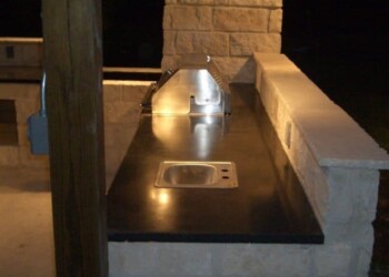 Outdoor kitchen with black countertop, sink, and grill in Ephrata, Pennsylvania. Outdoor kitchen countertop with sink and grill at night in Ephrata, PA.