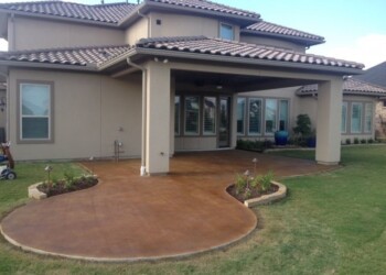 Finished acid stained concrete patio at a home in a residential neighborhood. Concrete patio with acid stain finish outside a beige house in a residential neighborhood.