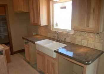 Kitchen with wooden cabinets, farmhouse sink, and window in a residential home. Kitchen with wooden cabinets, a white farmhouse sink, and a window above the countertop.