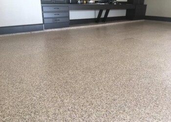 Epoxy coated garage floor in a commercial space with black cabinetry and a gray wall. Finished epoxy garage floor coating in a commercial space with black cabinetry.