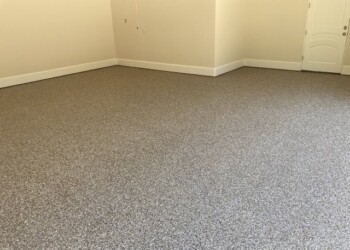 Garage floor coated with durable gray epoxy in a residential garage. Finished garage floor coating with a textured gray surface in a residential garage.