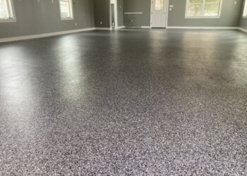 Finished garage floor with epoxy coating in a residential property. Newly coated garage floor with speckled epoxy finish in a residential home.