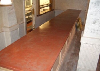 Concrete countertop installation in progress at a construction site. Long red and brown stone countertop in a construction site.