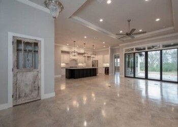 Modern living space with sealed concrete floors and open kitchen in ECD Concrete project. Spacious living area with sealed concrete floors, modern kitchen, and large sliding glass doors.