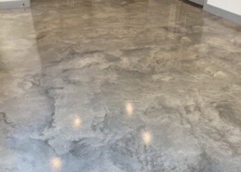 Sealed and waxed concrete floor in a kitchen in Eads, Tennessee. Polished concrete floor in a kitchen area with gray cabinets and a door to the outside.