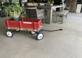 A red Radio Flyer wagon with potted plants on a concrete patio, part of an outdoor seating area. Red Radio Flyer wagon with potted plants on a concrete patio.