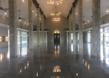 Sealed and waxed concrete floor in a spacious event hall in Eads, Tennessee. Polished concrete floor inside a large, elegant event hall with stone pillars and chandeliers.