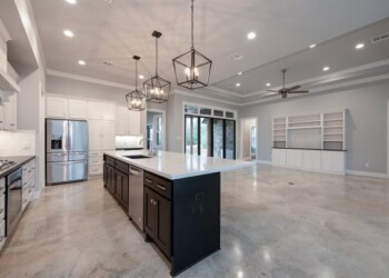 Spacious kitchen with sealed concrete floors, white cabinetry, and black island, part of a home in Ephrata, PA. Modern kitchen with sealed and waxed concrete floors, white cabinets, and black island in a spacious open-plan area.