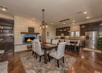 Spacious kitchen and dining room with fireplace, dark wood cabinets, and hardwood floors. Interior of a modern kitchen and dining area with a fireplace and dark wood cabinets.