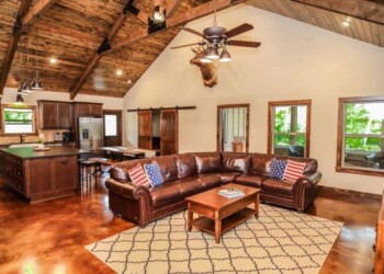 Spacious living room with vaulted ceiling, wooden beams, and leather sectional in a home in Eads, Tennessee. Interior view of a living room with a vaulted ceiling, wooden beams, and a leather sectional sofa.