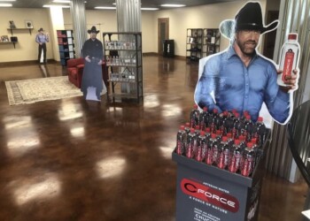 Polished concrete floor in a commercial space with cardboard cutouts and display of bottled drinks. Interior of a commercial space with polished concrete floor and cardboard cutouts of people.