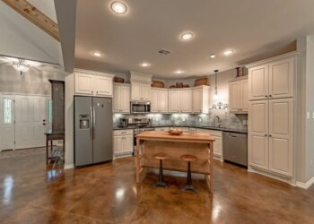 Spacious kitchen with white cabinetry and a central island in a residential home. Modern kitchen with white cabinets, stainless steel appliances, and a central island with two stools.