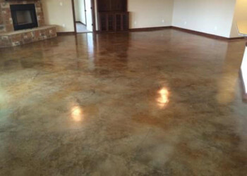 Finished acid stained concrete floor in a home, showing a glossy, multi-tonal finish. Interior of a room with freshly acid stained concrete floor in a residential home.