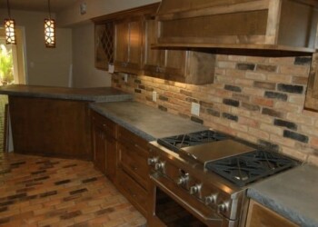 Kitchen with wooden cabinets, brick backsplash, and stainless steel stove in Eads. Kitchen with wooden cabinets, brick backsplash, and stainless steel stove in a home in Eads.
