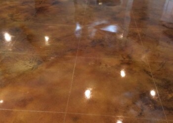 Interior acid stained concrete floor in a home, showing a glossy, multi-tonal finish. Polished concrete floor with a rich, glossy acid stain finish in a residential interior.