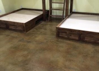 Room with two wooden bunk beds and ladder, concrete floor, yellow walls. Interior of a room with two wooden bunk beds and a ladder, concrete floor, yellow walls.