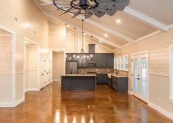 Interior of a kitchen with acid-stained concrete floor, high ceiling, and modern lighting in ECD Concrete, Anytown. Spacious kitchen with high vaulted ceiling, modern lighting, and polished concrete floor in ECD Concrete's interior acid-sta.
