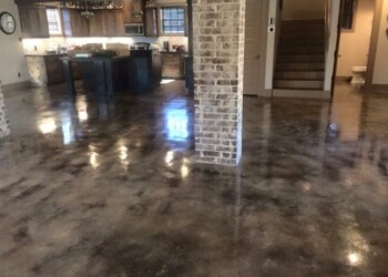 Polished concrete floor with acid stain finish in a home kitchen and living space. Interior view of a concrete floor with a polished acid stain finish in a home kitchen and living area.