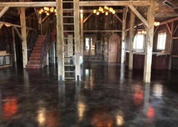 Finished interior with acid-stained concrete floor in a barn setting. Interior of a rustic barn with polished concrete floor and wooden beams.