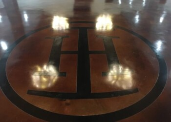 Concrete floor with a logo in black and brown, polished to a high shine. Polished concrete floor with a black and brown logo inside a circle.
