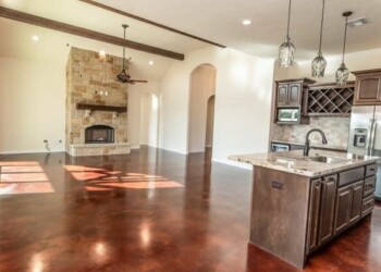 Polished concrete floors and a stone fireplace in a spacious living area. Interior view of a home with polished concrete floors and a stone fireplace in the living room.