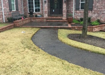 Finished acid stained concrete walkway leading to the front door of a brick house in Euless, Texas. Brick house with acid stained concrete walkway and landscaped yard in Euless, Texas.