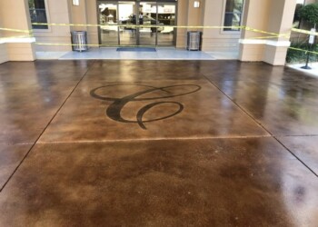 Decorative acid stained concrete floor at the entrance of a building in ECD Concrete. Concrete floor with decorative acid stain design at the entrance of a building.