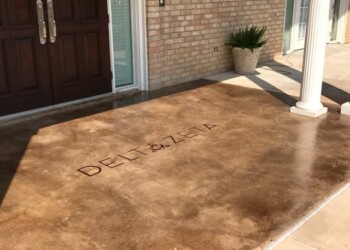 Concrete porch with acid stain finish and 'DELTA' etched into the surface in front of a house. Concrete porch with acid stain finish and 'DELTA' etched into the surface in front of a house.