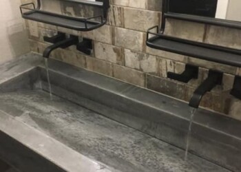 Concrete sink with two faucets and wall-mounted mirrors in a modern bathroom. Concrete sink with two faucets and wall-mounted mirrors in a modern bathroom.
