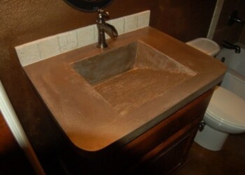 Concrete bathroom sink installed with a faucet in a home bathroom. Concrete bathroom sink with a built-in faucet in a residential bathroom.
