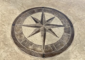 Engraved compass rose on concrete surface, part of a custom concrete project in the town. Concrete compass rose with engraved directional markers on a concrete surface.