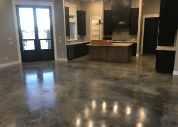 Newly sealed and waxed concrete floor in a kitchen and living space. Polished concrete floor in a modern kitchen and living area.