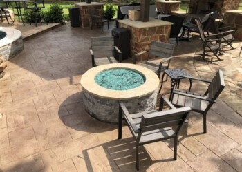Stamped concrete patio with fire pit and outdoor seating in a backyard. Stamped concrete patio with fire pit and outdoor seating in a backyard.